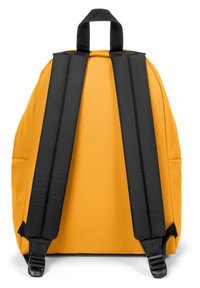 Gul ryggsäck med svarta justerbara remmar och ett handtag upptill. Har en slät yta och symmetrisk design utan synliga logotyper.