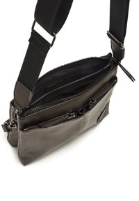 Borsa a tracolla grigia scura con un esterno texturizzato, più scomparti e chiusure a zip. Cinghia regolabile e dettagli di cucitura rinforzata.