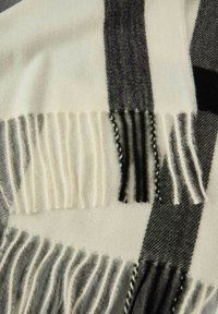 Sciarpa di lana con motivo a quadri nero, bianco e grigio e bordi frangiati.