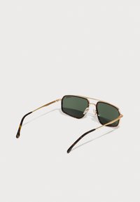 Ochelari de soare cu un cadru din metal auriu, lentile verde închis și accente din scoică de țestoasă pe brațe. Au pernuțe ajustabile pentru nas pentru confort.