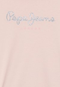 Camiseta de color rosa claro con un brillante logo plateado de "Pepe Jeans" y la palabra "LONDON" en un rosa más claro, sobre una tela de algodón suave.