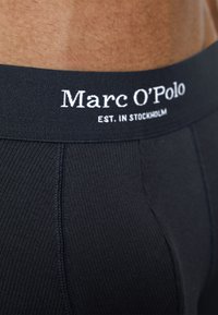 Černé žebrovan�é boxerky s širokým elastickým pasem, na kterém je bílé textové logo "Marc O'Polo EST. IN STOCKHOLM". Strukturovaný povrch látky.