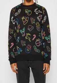 Schwarzer Pullover mit bunten, gestickten Feiertagsmotiven, darunter Rentiere, Schneemänner, Hüte und Zuckerstangen. Crewneck-Design mit gerippten Bündchen.