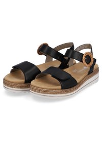 Sandales en cuir noir avec une large sangle, une sangle de cheville réglable et un accent tissé circulaire. Semelle épaisse blanche avec des détails texturés.