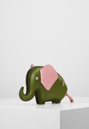 Grüne elefantenförmige Tasche mit rosa Ohren und Quaste am Schwanz, auf einer weißen Oberfläche vor neutralem Hintergrund platziert.