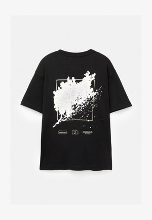 Fekete, rövid ujjú póló, nagy fehér grafikai dizájnnal és szöveggel a hátsó részén, egy négyzet alakú kereten belüli absztrakt formával.
