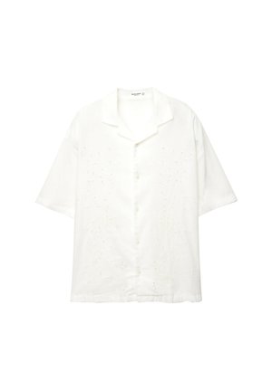 Biała koszula z krótkim rękawem, wykonana z bawełny, z kwiatowym haftem z przodu i luźnym kołnierzykiem. Posiada zapięcie na guziki.