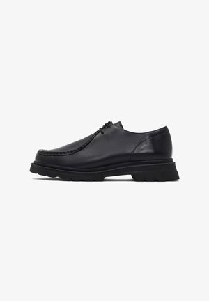 Chaussures en cuir noir avec un bout rond, dessus texturé et semelle en caoutchouc noir épaisse. Présente des coutures visibles le long du bord et un design à lacets.