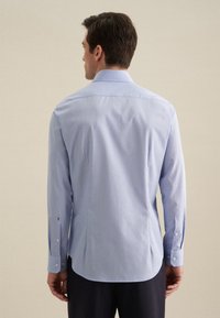 Camicia da uomo azzurra chiara a maniche lunghe con colletto a punta, polsini con bottoni e righe verticali, vista dal retro. Fit su misura, tessuto liscio.
