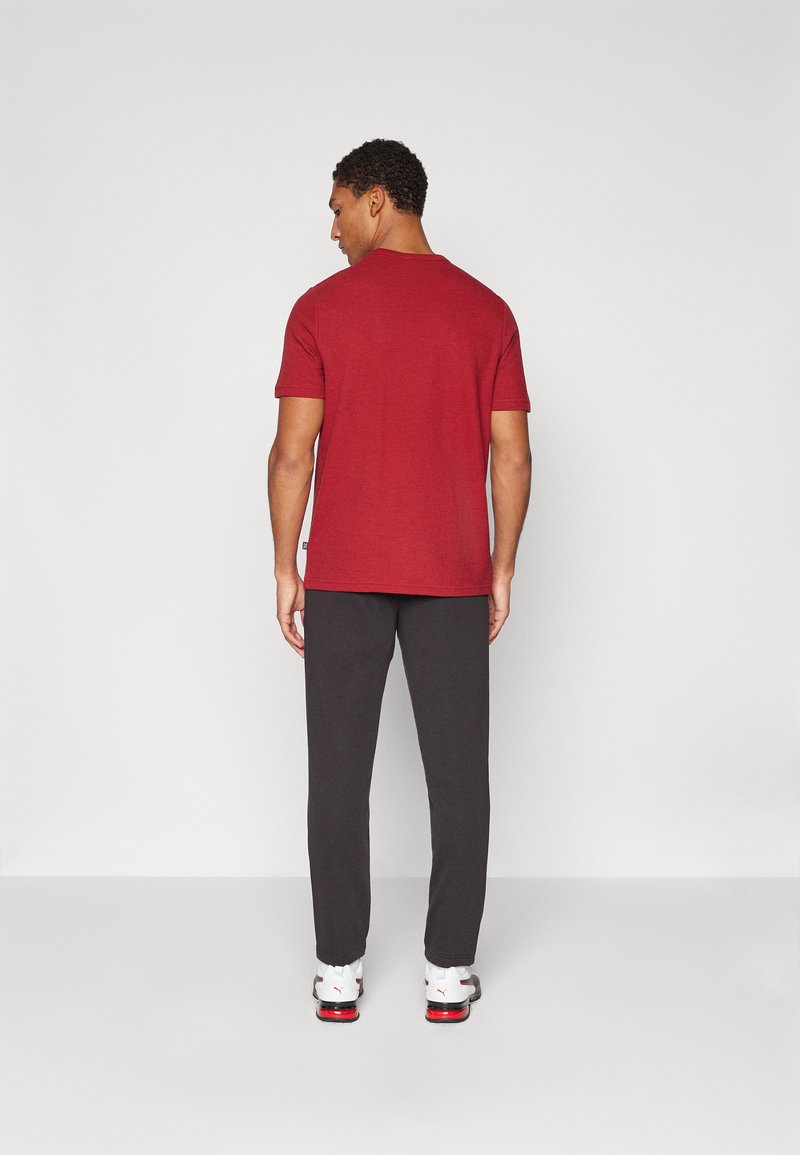 Camiseta de manga corta roja combinada con pantalones gris oscuro, con un ajuste relajado y un escote redondo. Llevada con zapatillas blancas.