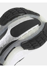 Gros plan d'une semelle de basket blanche avec des rainures en caoutchouc noir et des sections translucides, arborant un logo de la marque Continental au niveau du talon.