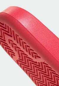 Raudona guminė batų pada su raštuotu zigzaginių griovelių raštu, skirtu sukibimui. Lygus išorinis kraštas su šiek tiek užapvalinta forma.