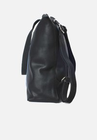 Svart läderväska med en strukturerad form, justerbar axelrem och silverdetaljer. Har en slät yta och minimalistiska designelement.