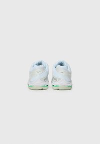 White athletic shoes with light blue accents, textured mesh upper, cushioned sole, and green detailing on the outsole, branded “Mizuno” on the side.