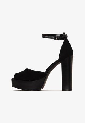 Black high-heeled platform sandals with a suede upper, open toe, ankle strap, and a glossy, chunky heel. Textured fabric and smooth accents.