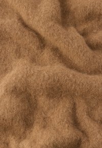 Brązowa wełniana tkanina o miękkiej, puszystej teksturze, charakteryzująca się luźnym splotem i falami na całej powierzchni, co tworzy ciepły, przytulny wygląd.