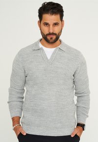 Hellgrauer gestrickter Pullover mit V-Ausschnitt und kragenförmigem Design, mit gerippten Bündchen und Saum. Die strukturierte Stoffqualität verleiht visuelles Interesse.