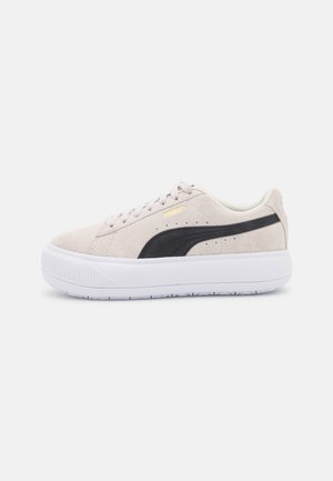 Baskets Puma en daim beige avec détail de bande noire et épaisse semelle blanche compensée, photographiées sur fond blanc.
