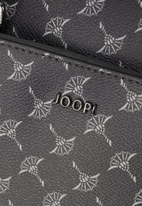 Black textured wallet featuring a repeating white leaf pattern and the embossed brand name "JOOP!" in silver hardware.
