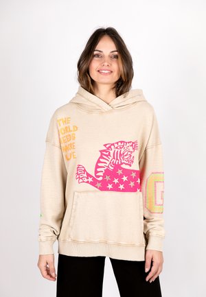 Beige oversized hoodie with a kangaroo pocket. Features colorful graphic of a tiger and text in orange, pink, and stars. Soft material.