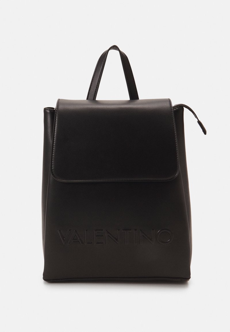 Sac à dos en cuir noir avec fermeture à rabat, logo "VALENTINO" embossé, et une poignée supérieure. Texture lisse avec un design minimaliste.