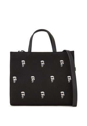 Black fabric handbag featuring multiple white cartoon figures, flat rectangular shape, dual top handles, and a removable shoulder strap.