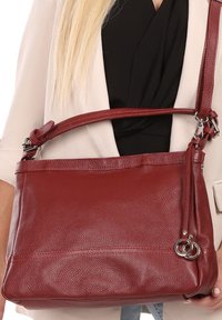 Rode leren handtas met een textuur oppervlak, verstelbare schouderriem en zilverkleurige hardware details. Compact rechthoekige vorm.