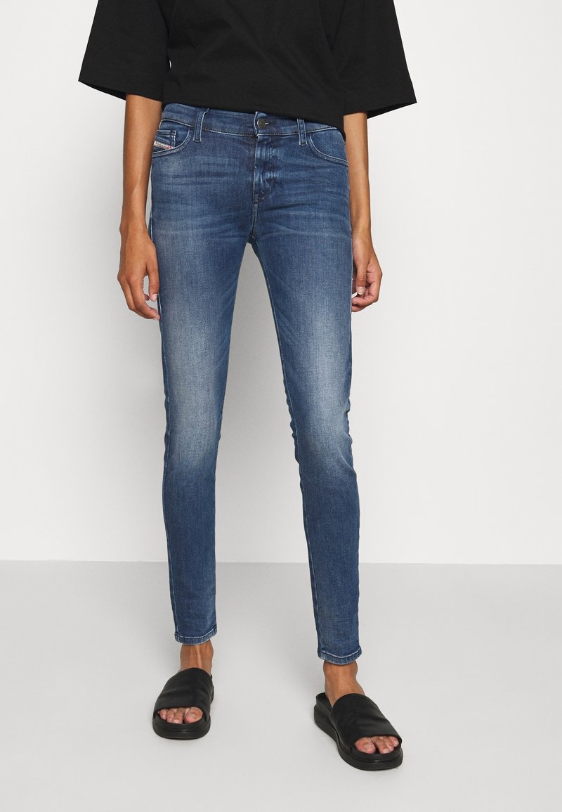 Faded blue skinny jeans in denim with a classic five-pocket design. Paired with a black oversized top and black slide sandals.