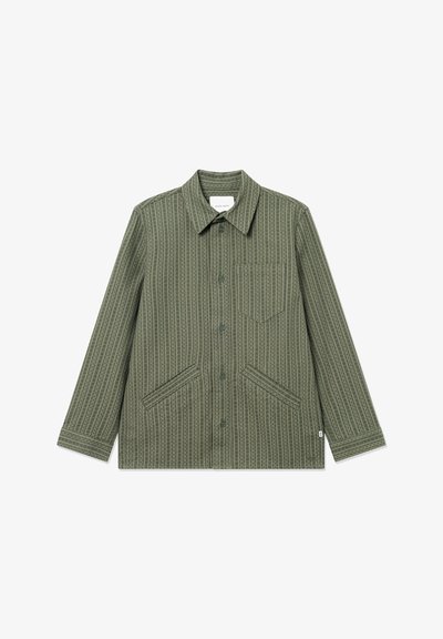 Olíva zöld dzseki gombos elülső résszel, hegyes gallérral, hosszú ujjemmel, és két elülső zsebbel, geometrikus mintával az egész felületen.