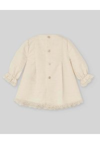 Cappotto per bambini di un leggero beige con maniche lunghe, tessuto texturizzato, bordi in pizzo su polsini e orlo, e cinque bottoni frontali. Vista posteriore mostrata.