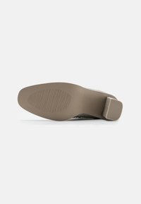 Semelle de chaussure en caoutchouc brun avec des motifs de texture pour une meilleure adhérence, dotée d'un petit talon carré et d'une surface lisse et plate.