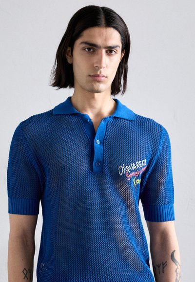Das blaue Mesh-Poloshirt verfügt über ein strukturiertes Design, einen gerippten Kragen und Ärmel sowie mehrfarbige Stickereien auf der Brust.