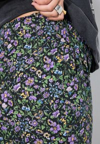 Rok met bloemenprint met een mix van paarse, blauwe en gele bloemen op een zwarte achtergrond. Lichte stof met een elastische tailleband.