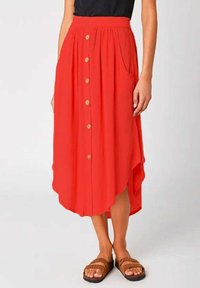 Roter Midi-Rock mit asymmetrischem Saum, Frontknöpfen und Seitentaschen. Hergestellt aus einem leichten Stoff mit glatter Textur.
