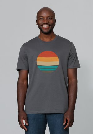 Grijze T-shirt met een cirkelvormig ontwerp met horizontale strepen in oranje, geel, groen en blauw. Korte mouwen en ronde hals.
