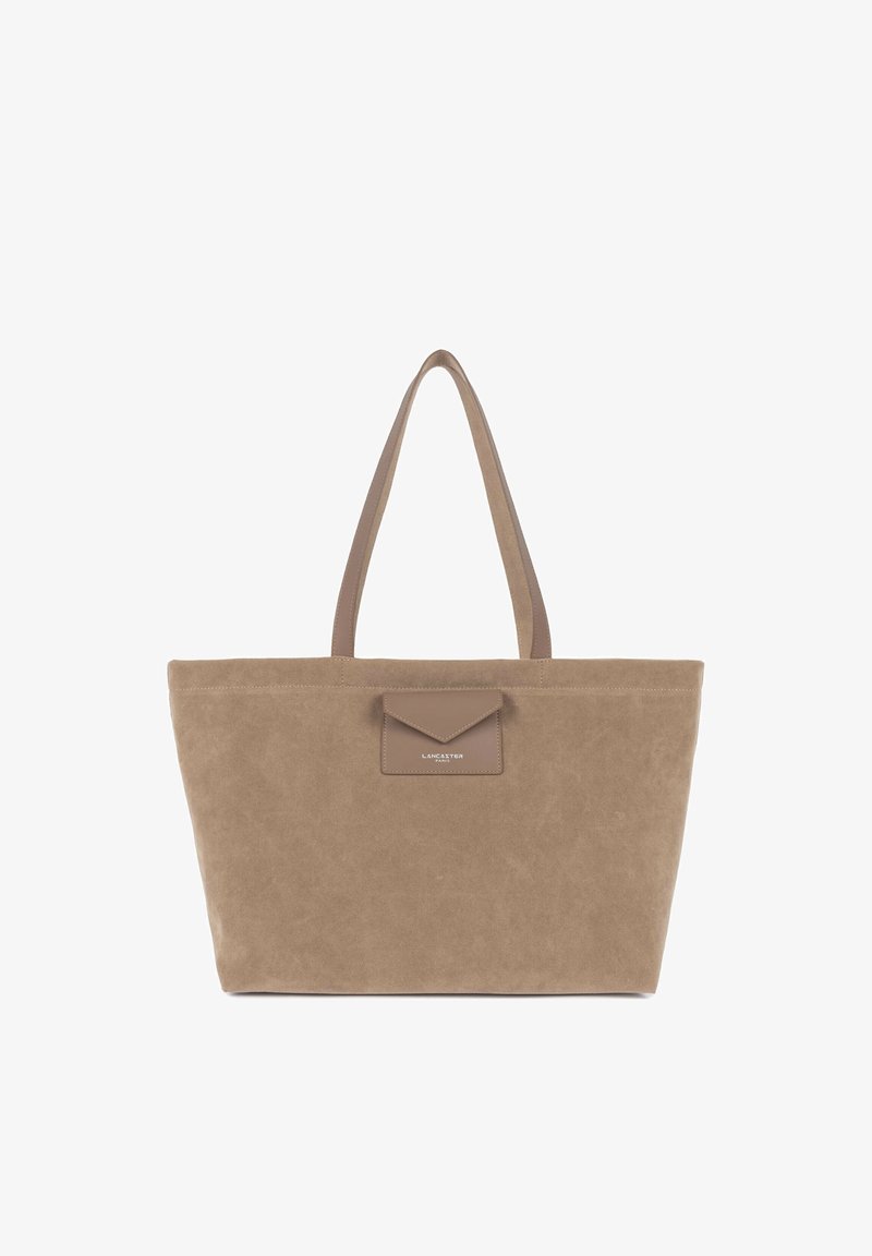Borsa tote in camoscio beige con due manici lunghi, una tasca frontale con patta e dettaglio logo in rilievo. Forma rettangolare semplice con texture morbida.