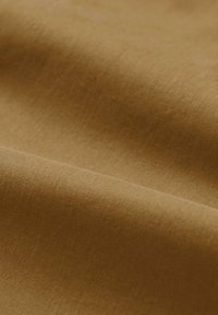 Tessuto di cotone marrone con una texture liscia, caratterizzato da una leggera lucentezza e un leggero allungamento, che si adagia in onde dolci.