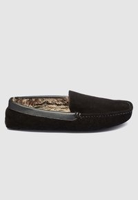 Crni suede papučar s mekim krznom unutra, s glatkim kožnim detaljem na gornjem dijelu i kontrastnim šavovima duž rubova.