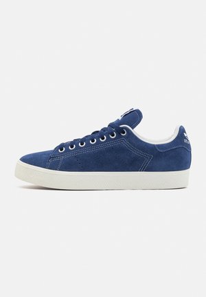 Baskets en daim bleu marine avec semelle en caoutchouc blanc, bout rond, six œillets et détails perforés sur les côtés.