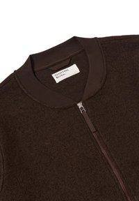 Giacca bomber in lana marrone con chiusura a zip, colletto a coste e texture morbida. L'etichetta reca la scritta "Universal Works." Presenta un design minimalista.