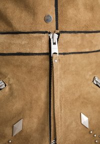 Giacca in suede marrone con hardware silver, zip centrale e borchie decorative a forma di diamante, con cuciture nere in evidenza.