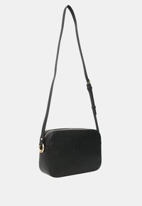 Černá kožená crossbody taška s embosovaným vzorem loga, obdélníkový tvar, zipové uzavření a nastavitelné rameno. Akcenty zlatého kovu.