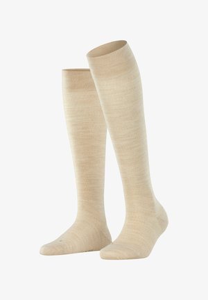 Kniehoge beige sokken van een zachte, gladde stof met een gelijkmatige textuur en een geribbelde rand aan de bovenkant.