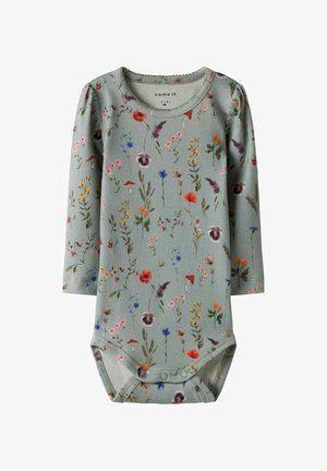 Long-sleeve baby bodysuit in light green cotton with a floral pattern featuring red, blue, and yellow flowers. Snap closure at the bottom.