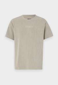 Světle šedé tričko s krátkým rukávem vyrobené z ribované tkaniny, které má na hrudi jemně vytlačené logo "GUESS". Jednoduchý kulatý výstřih.