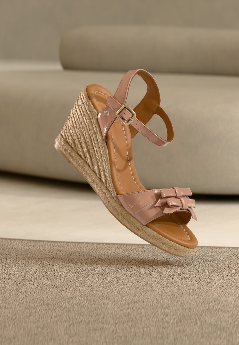 Πλατφόρμες σε ανοιχτό ροζ πατεντέ δέρμα· διαθέτουν φιόγκους, λουράκι με ορθογώνια αγκράφα και πλεκτή σόλα από τζουτ.