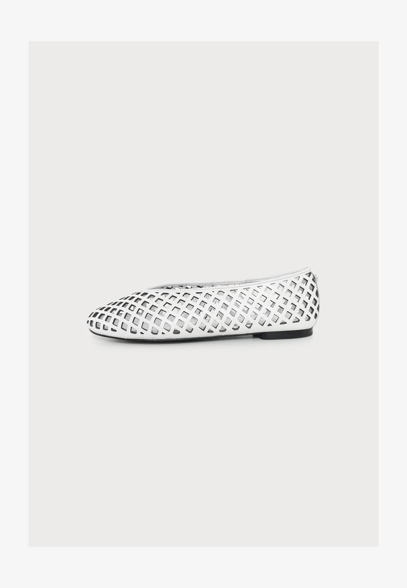 Chaussure plate blanche avec un motif en treillis de découpes carrées et une semelle noire, vue de côté sur un fond uni.