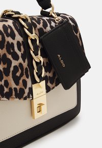 Kabelka s leopardím potiskem, která má strukturovaný design, zlatý řetězový popruh, černé akcenty a visačku s logem. Texturované materiály a kovové detaily.