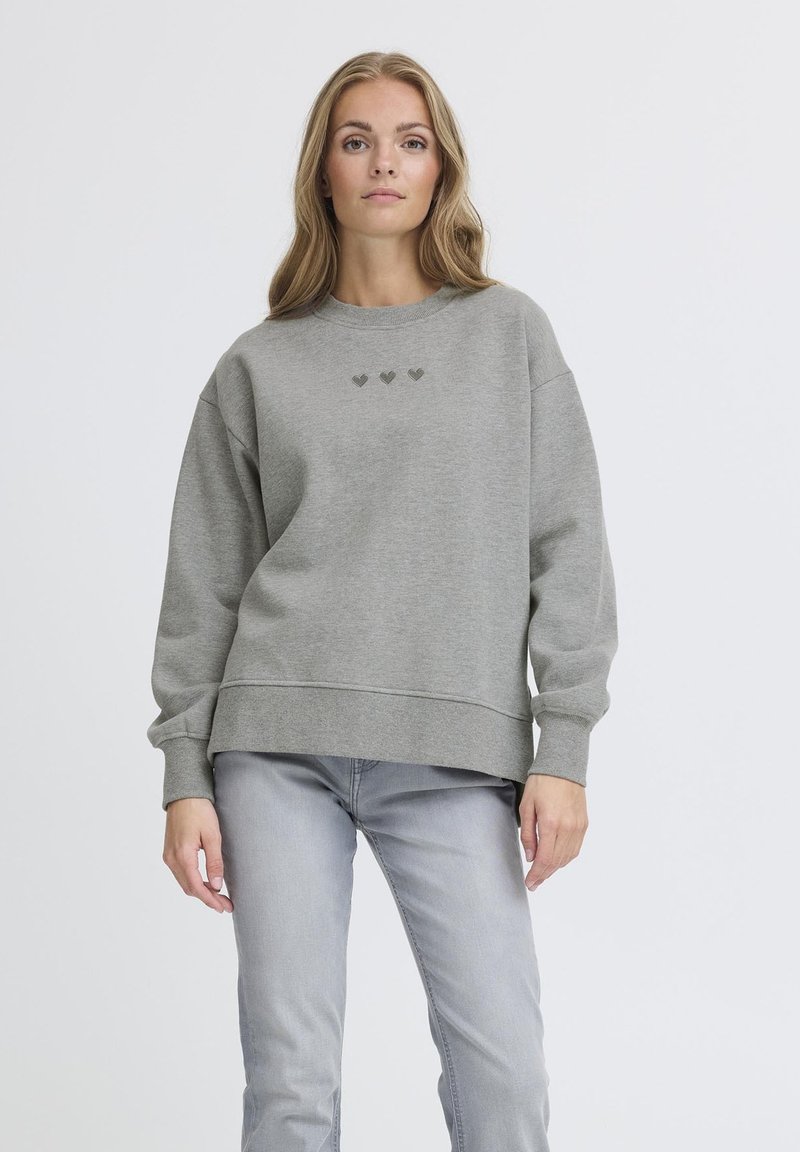 Suéter gris de corte relajado, con tres pequeños diseños de corazones en un tono más oscuro en el pecho. Tejido suave, con puños y dobladillo acanalados.