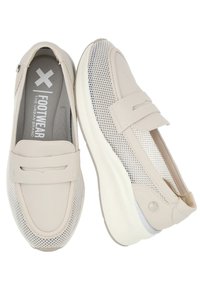 Zapatos slip-on de color beige claro con parte superior de malla y acentos de cuero. Punta redondeada, plantilla acolchada y suela de goma blanca. Diseño simple y deportivo.
